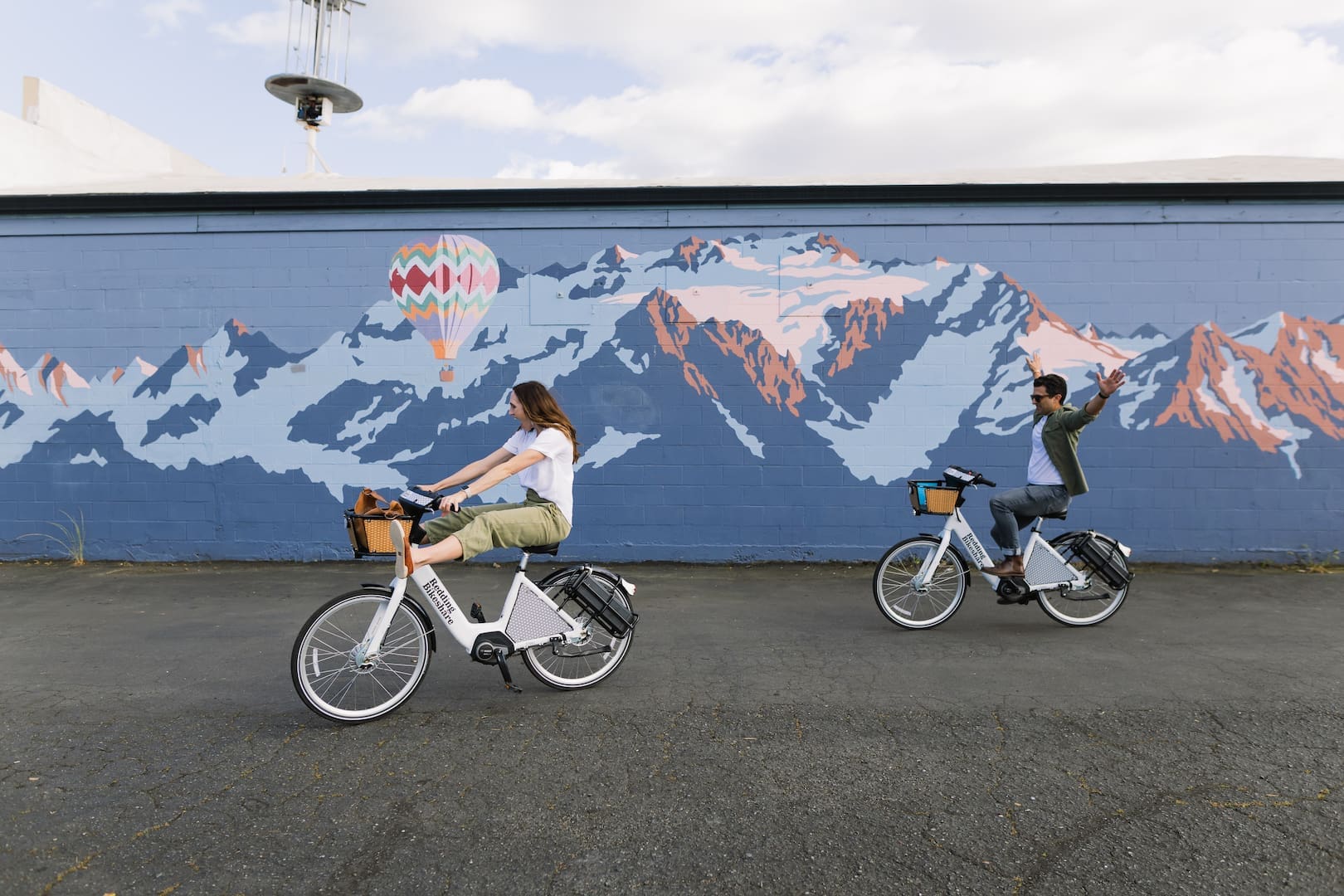 Two people riding bikes by murals in Redding