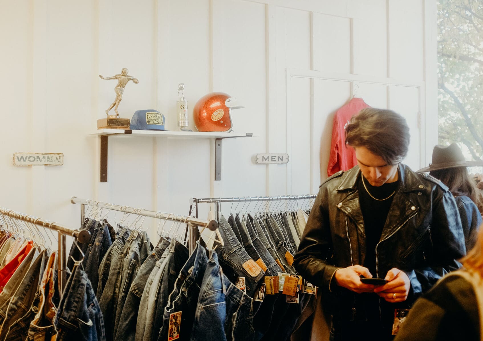A young man in a black leather jacket on his cell phone shopping for denim at Old 44 Vintage in downtown Redding, CA.