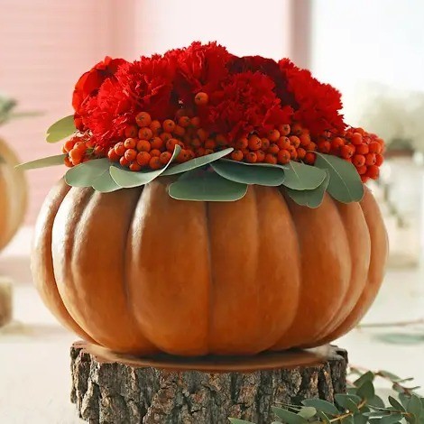 Pumpkin full of red flowers and berries.