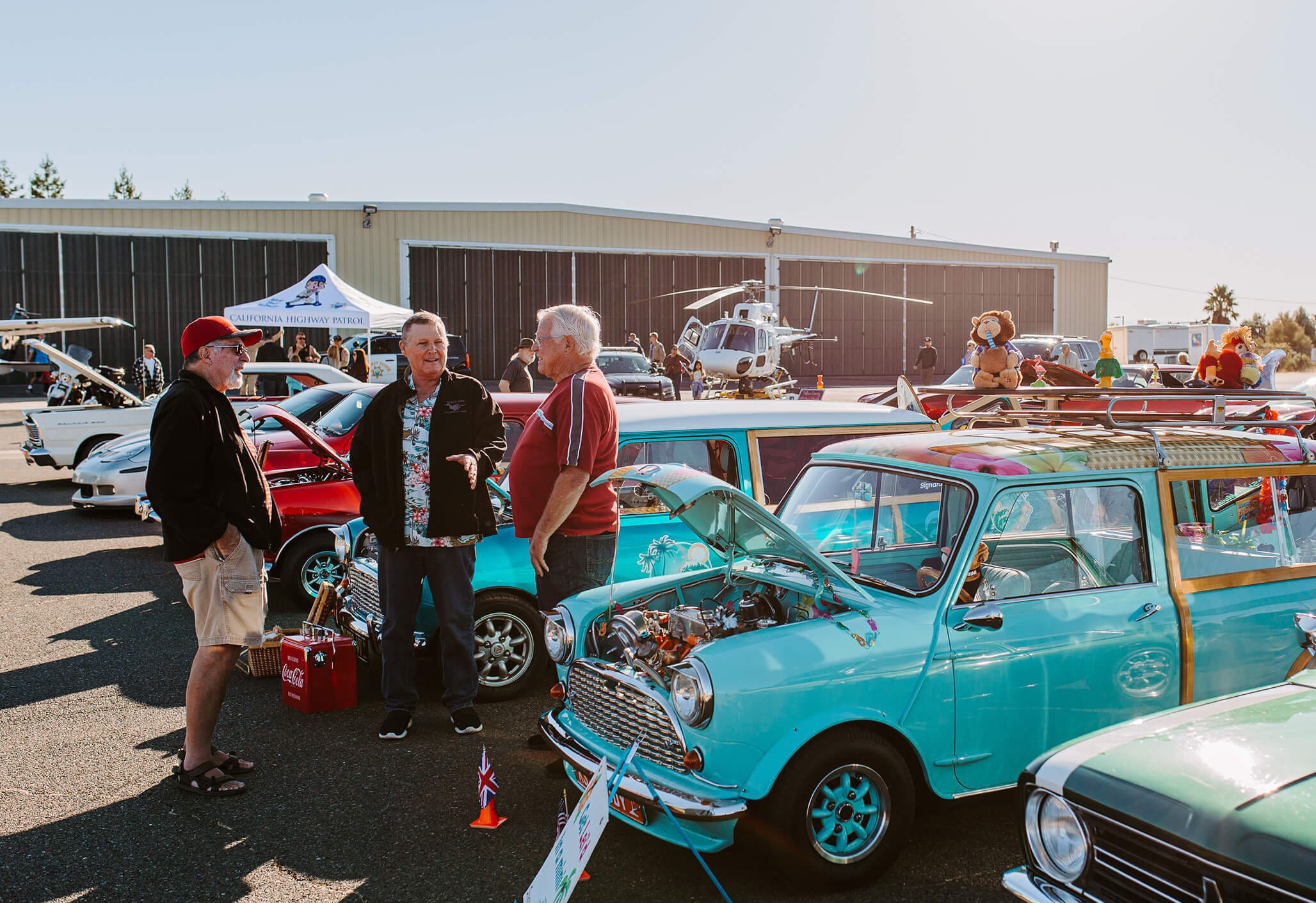 A group of older gentlemen stand and chat aside their vintage automobiles at a car show event in Redding, CA